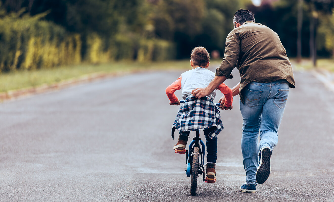 Miniatyrbild av en förälder som lär sitt barn att cykla – lek och aktivitet trots astma.